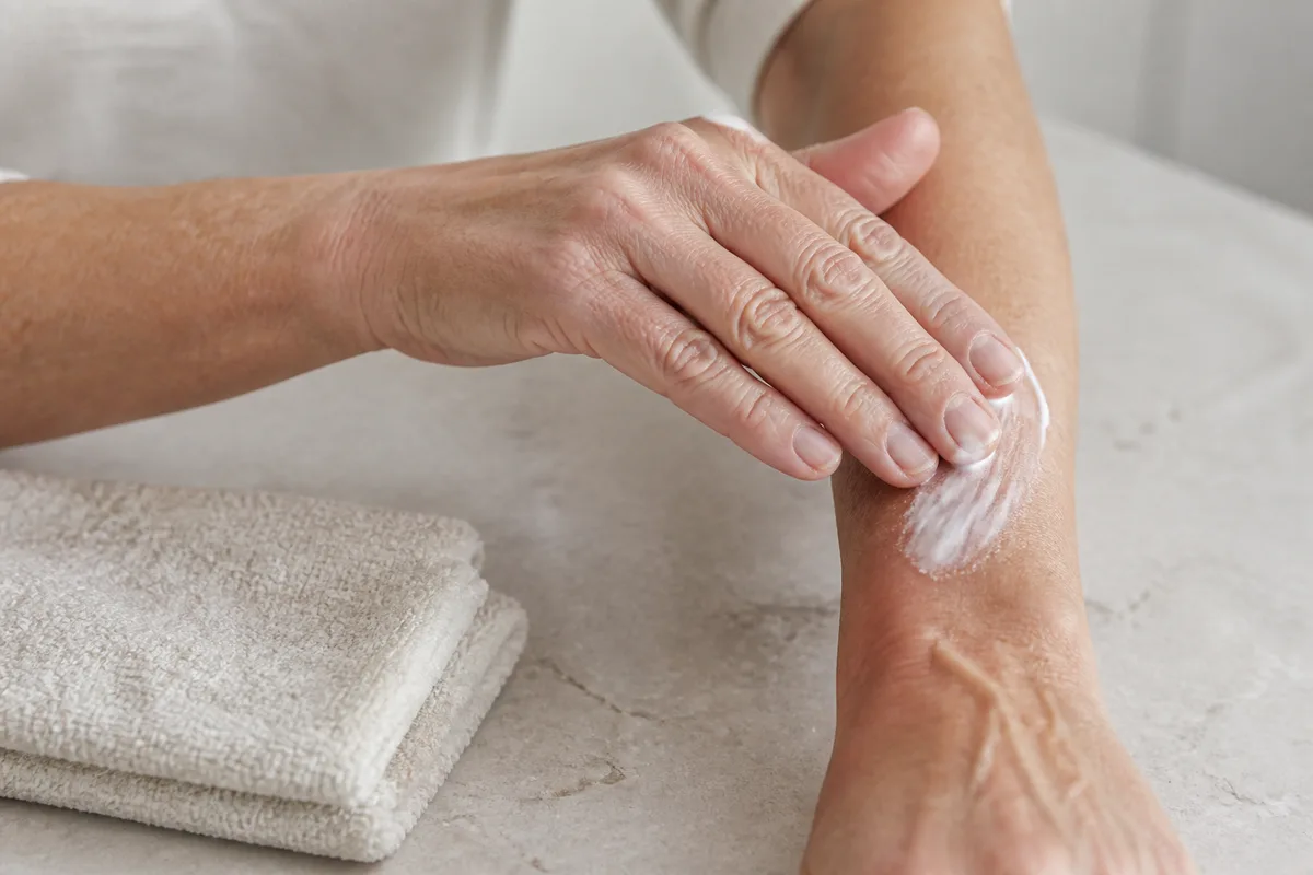 Mains matures appliquant une crème hydratante sur l&rsquo;avant-bras